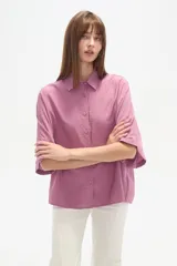 Camisa holgada de viscosa color rosado, con cuello camisero, manga corta y cierre frontal de botones.