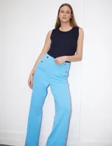 Pantalón largo de crepe elastizado color verde, de corte recto, con bolsillos delanteros y apliques de botones metálicos.