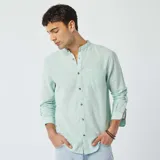 Camisa celeste claro de lino con cuello mao, manga larga con puños abotonados y bolsillo de parche en el pecho.