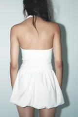 Minivestido negro con forma de chaleco, cuello halter, escote en pico, botones metálicos y bajo globo.