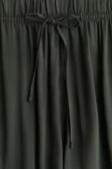 Pantalón verde militar de viscosa, corte amplio, tiro alto, cintura elastizada con cordón de ajuste, bolsillos laterales y piernas rectas.
