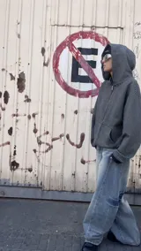 Campera con capucha y cierre frontal, de tejido grueso color gris oscuro con rayas horizontales finas en blanco. Presenta cuello alto y puños y cintura acanalados.