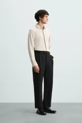 Camisa color beige de corte slim fit, confeccionada en tejido elástico con cuello italiano abierto, manga larga con puños abotonados y cierre frontal con botones.