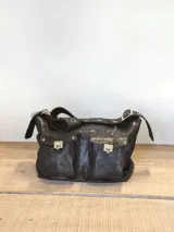 Bolso bandolera negro con detalles dorados, múltiples bolsillos frontales con cierre de hebilla y correa ajustable con hebilla. Confeccionado en cuero sintético con textura brillante.