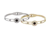 Pulsera rígida dorada de acero con detalle circular central calado con onix negro y nácar.