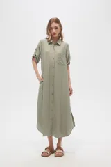 Vestido camisero midi negro de corte holgado, con cuello camisero, mangas cortas con trabillas, cierre frontal con botones, bolsillo en el pecho y bolsillos laterales.