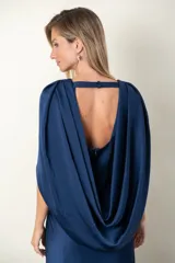 Vestido largo de satén de seda color azul con busto drapeado formando un nudo y capa que sale de los hombros.