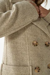 Abrigo de lana color beige con cuello solapa y manga larga. Cierre frontal cruzado doble con botones dorados. Bolsillos delanteros plaqué y forro al tono. Tela 100% lana fina sin teñir, diseñada exclusivamente por Don Baez. Hecho 100% en Uruguay.