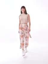 Pantalón babucha de tela estampada con hojas en tonos rosa, naranja y azul, con cintura elastizada y lazo para ajustar.