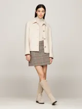 Minifalda de tweed a cuadros en tonos beige, marrón, negro, rojo y azul. Tiene dos bolsillos delanteros de parche con botones dorados con el logo de la marca.