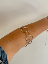 Brazalete plateado de acero quirúrgico con eslabones circulares de diferentes tamaños.