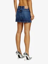 Falda corta de denim azul oscuro, con lavado desgastado y tiro bajo. Presenta cinco bolsillos y cierre frontal con botón y cremallera.