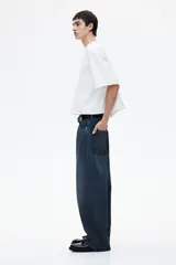 Pantalón de jean azul oscuro de corte holgado, con tiro bajo, cinco bolsillos y pierna extra ancha con pliegues en el tobillo.