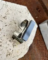 Pulsera rígida de alpaca plateada con piedra rectangular color celeste con vetas horizontales.