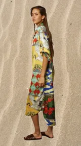 Túnica estampada de calce holgado con cuello camisero y mangas cortas. Presenta un diseño patchwork con motivos florales, aves y geométricos en tonos amarillo, azul, rojo y verde.