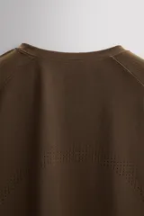 Camiseta deportiva marrón con estructura perforada, cuello redondo, manga corta y logo estampado.