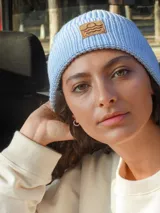 Gorro de lana celeste tejido en punto con dobladillo y parche de cuero con logo en el frente.