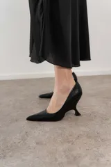 Zapato de tacón negro de cuero, con punta fina y taco con forma geométrica.