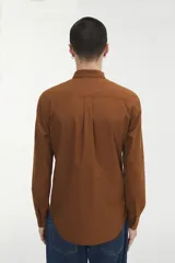 Camisa marrón con pequeños lunares rojos, de corte recto, manga larga y bolsillo en el pecho.