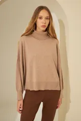 Sweater negro oversize de tejido de punto, con cuello alto y detalle de costuras a la vista.