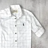 Camisa de algodón blanca con cuadros finos en negro, con cuello italiano y botones en la parte delantera.