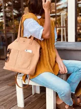 Cartera tipo tote bag color beige con textura símil cocodrilo, doble asa corta y correa larga extraíble y ajustable. Tiene dos bolsillos externos grandes y cierre superior con botón a presión.