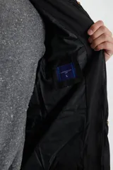 Campera negra tipo abrigo, con capucha y cierre frontal, ideal para climas fríos.