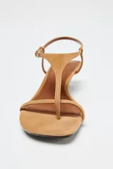 Sandalia de tacón kitten color tostado, con tiras finas de ante y cierre de hebilla ajustable en el tobillo.