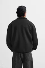 Sudadera negra de cuello alto con cierre frontal de cremallera, corte relaxed fit, manga larga y terminaciones en rib.
