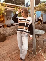 Sweater de punto con diseño a rayas horizontales en tonos blanco, negro, marrón y rosa.