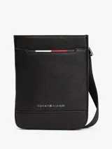 Bandolera negra de Tommy Hilfiger con acabado granulado, correa ajustable de tejido trenzado, bolsillo exterior abierto, cinta distintiva y logo metálico.