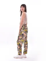 Pantalón babucha de tela estampada con hojas en tonos rosa, naranja y azul, con cintura elastizada y lazo para ajustar.