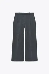 Pantalón gris oscuro de tiro alto con trabillas, bolsillos laterales, detalle de pinzas y cierre frontal con cremallera, botón interior y gancho metálico.
