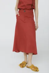 Falda midi color ladrillo, de corte evasé y tiro alto, con bolsillos laterales y botón decorativo en la cintura.