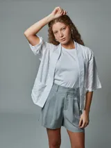 Kimono blanco con bordado calado, mangas cortas y bolsillos delanteros.