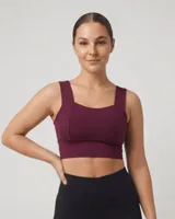 Top deportivo color bordó con escote cuadrado y breteles anchos. Presenta costuras verticales que realzan la forma del busto y una banda inferior ancha para mayor sujeción.