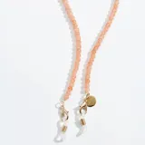 Correa para lentes con cuentas redondas color naranja, enganches dorados y terminales de silicona transparente. Incluye un dije dorado con el logo de la marca.