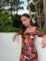 Vestido corto con estampado floral en tonos rosa y lila, escote cuadrado con detalle fruncido y abertura en el centro, mangas largas abullonadas y falda con tajo lateral.