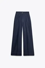 Pantalón de tiro alto color azul denim, con pinzas delanteras, bolsillos frontales, pernera ancha y pespuntes combinados a contraste en color beige.