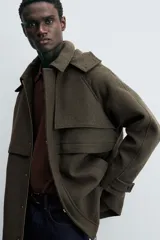 Parka verde oscuro confeccionada en tejido con lana, corte regular, cuello solapa con capucha desmontable, manga larga con puño ajustable, bolsillos de vivo en cadera y cierre frontal con cremallera oculta por solapa con botones a presión.