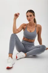 Top deportivo color beige con banda inferior azul y tirantes finos azul marino. Espalda cruzada con doble tira.