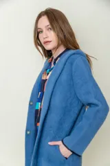 Tapado largo de paño azul con capucha y bolsillos laterales.
