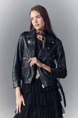 Campera negra de cuero ovino, estilo rocker, con cinturón, charreteras y solapas. Tiene cierres y detalles metálicos en frente y espalda.