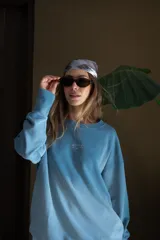 Buzo de algodón orgánico color celeste con efecto tie-dye o lavado, corte oversize y bordado minimalista en el pecho.