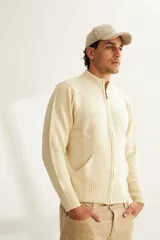 Campera de lana color crema, tejida con cierre delantero, cuello alto y bolsillos delanteros.