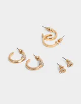 Set de tres pares de aros dorados: un par de aros pasantes con strass, un par de argollas lisas y un par de argollas con strass.