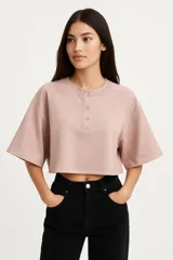 Remera cropped color rosa con cuello redondo, manga 3/4 y cierre frontal con broches.