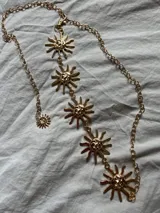 Cadena plateada para la cintura con dijes de soles sonrientes.