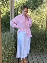 Camisa holgada a rayas verticales color beige y blanco, con cuello clásico, manga larga, bolsillo en el pecho y cierre frontal con botones nacarados.