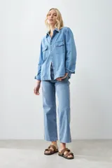 Camisa de jean celeste con doble bolsillo frontal con solapa y cierre con botones.